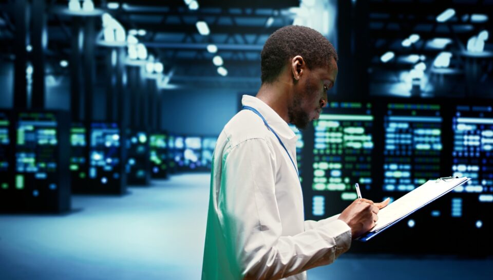 Supercomputers performing data backups Worker taking note of supercomputers performing data backups and providing centralized storage. Mechanic offering technical support in Uninterruptible Power Supply ensuring operational continuity
