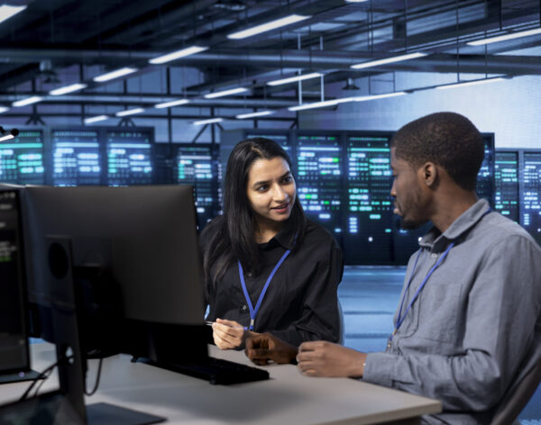 IT staff members using desktop PC to do maintenance in data center to extend equipment life span and avoid downtime. Teamworking colleagues monitoring blade servers for overheating problems